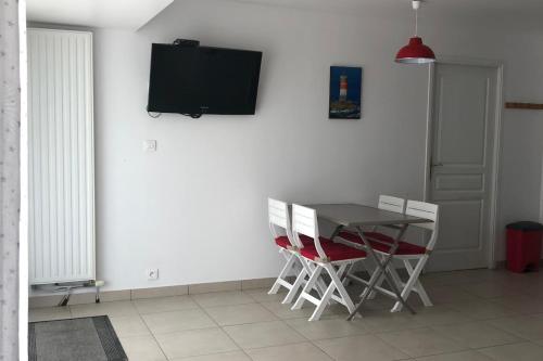 une salle à manger avec une table et des chaises ainsi qu'une télévision murale. dans l'établissement Comfortable nest just a stone's throw from the sea, au Pouliguen