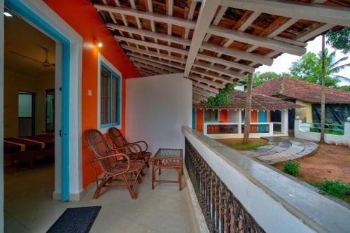 a porch of a house with chairs and a patio at Papilio Beach Front Cottages-TBV in Baga