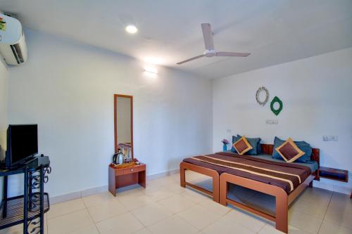 a bedroom with a bed and a tv in it at Papilio Beach Front Cottages-TBV in Baga