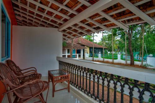 a balcony with two chairs and a table on it at Papilio Beach Front Cottages-TBV in Baga