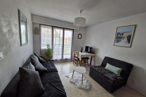 un salon avec un canapé et une table dans l'établissement Comfortable two-room nest with sea view, à Villers-sur-Mer