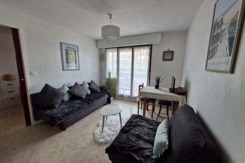un salon avec un canapé et une table dans l'établissement Comfortable two-room nest with sea view, à Villers-sur-Mer
