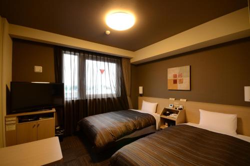 a hotel room with two beds and a television at Hotel Route Inn Annaka in Annaka