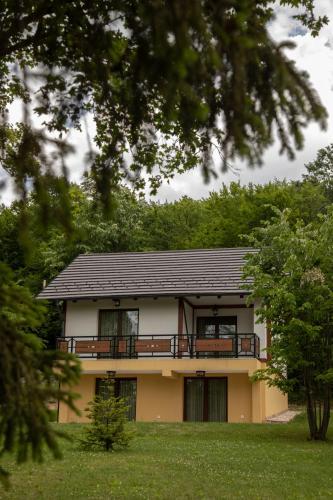 a house with a balcony and trees in the background at Vila Ana in Kalesija