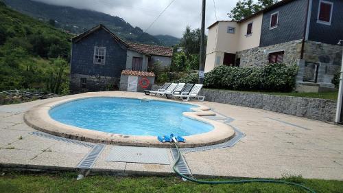 a swimming pool with two chairs and a hose at Casa do Moinho in Resende