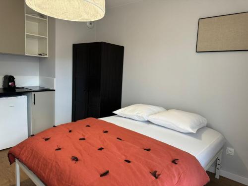 - une chambre avec un lit et une couverture orange dans l'établissement M72 Marquer Studio centre ville d'Annemasse, à Annemasse