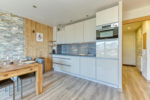une cuisine avec des armoires blanches et une table en bois dans l'établissement Homency - Résidence Azur G5, à L'Alpe-d'Huez