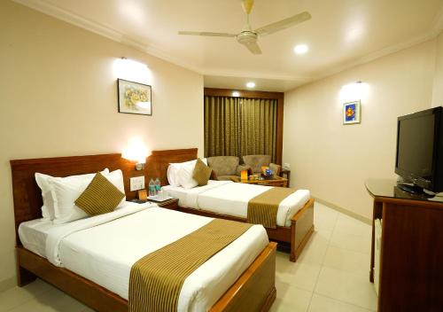 a hotel room with two beds and a flat screen tv at Hotel Mayura in Raipur