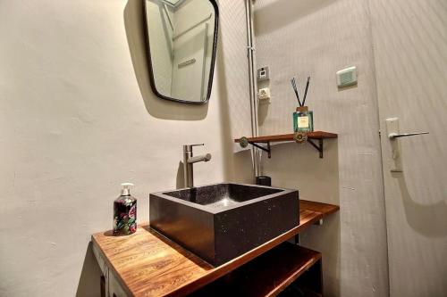 une salle de bain avec un lavabo noir et un miroir dans l'établissement SC Collection - Charme et Authenticité du Panier, à Marseille