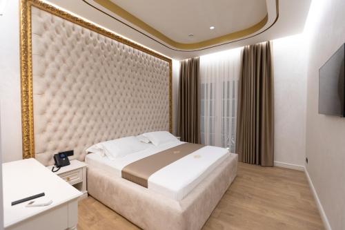a bedroom with a large bed and a mirror at King & Queen Boutique Hotel in Fier
