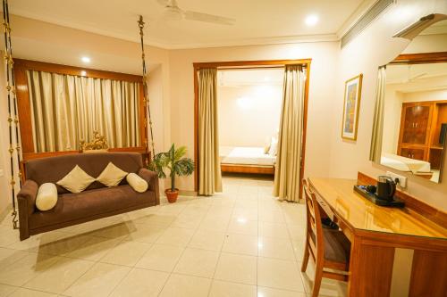 a living room with a couch and a bedroom at Hotel Mayura in Raipur