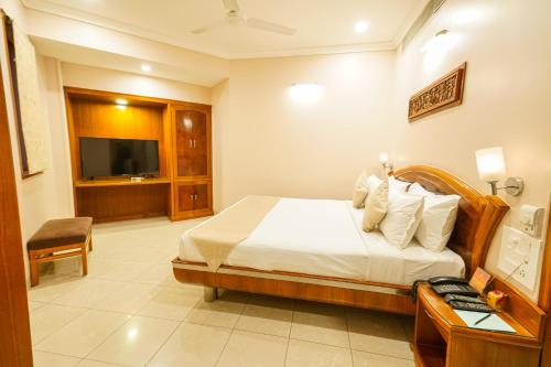 a hotel room with a bed and a television at Hotel Mayura in Raipur