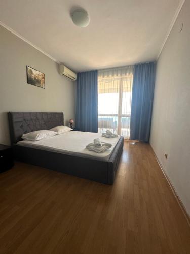 a bedroom with a large bed with blue curtains at Apartments in Panorama Beach Vigo Nessebar in Nesebar