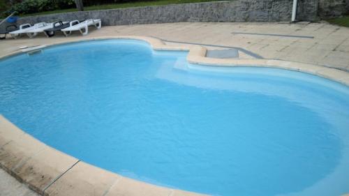 a large blue swimming pool with two lawn chairs at Casa do Moinho in Resende