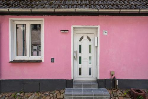 a pink house with a white door and windows at Wanderpfotens Ostsee Ferienhaus in Tribsees