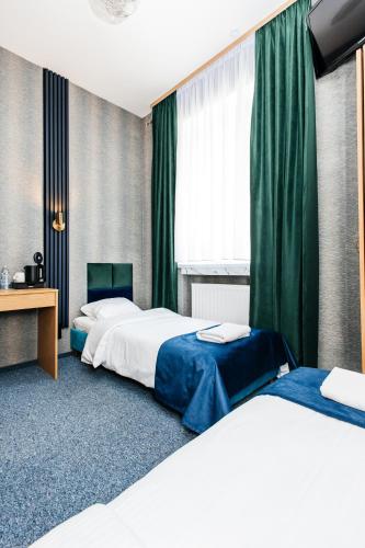 two beds in a hotel room with green curtains at Elegant Apartments in Poznań
