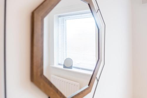 a mirror hanging on a wall with a window at Brancepeth Place in Shildon