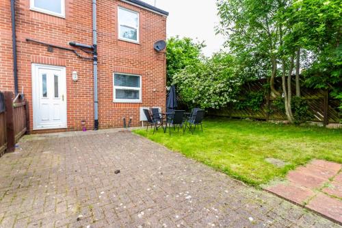 a brick house with a patio and chairs in the yard at Brancepeth Place in Shildon