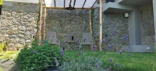 a garden with purple flowers in front of a stone wall at Da Arturo e Maruca suites con 2 camere in Vellano