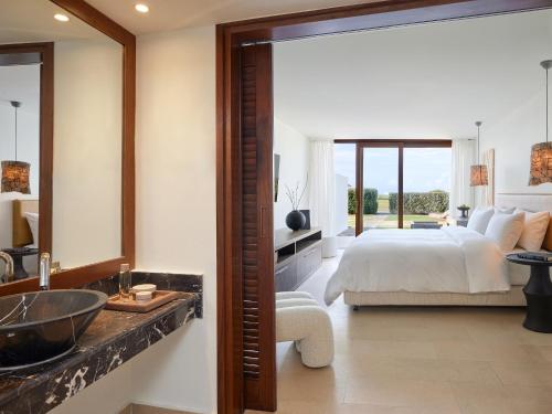 a bedroom with a bed and a bathroom with a sink at Amirandes, A Grecotel Resort to Live in Gouves