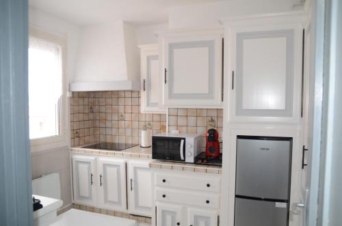 une cuisine avec des armoires blanches et un micro-ondes dans l'établissement APPARTEMENT T3 LUXUEUX dans RESIDENCE, à Tarbes