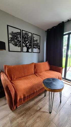 an orange couch in a living room with a table at Mazurskie Wzgórze Nad Jeziorem Isąg in Pelnik