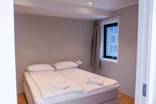 Un dormitorio con una cama con sábanas blancas y una ventana. en Avisgata Apartments, en Svolvær