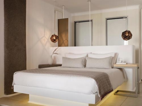 a white bedroom with a white bed with two mirrors at Mykonos No5 Luxury Suites & Villas in Ornos