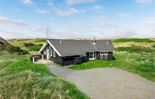 a small black house in the middle of a field at Holiday Home Krogen Ringkøbing in Søndervig