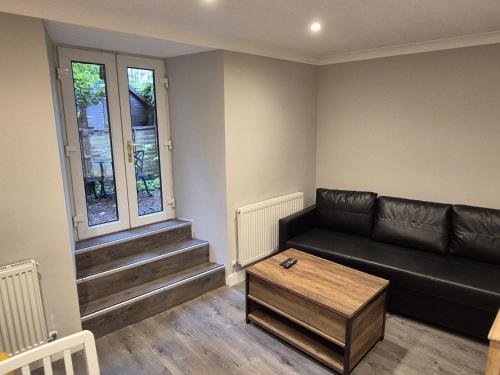 a living room with a black couch and a table at St Patrick Square Main Door in Edinburgh