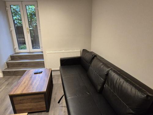 a living room with a leather couch and a wooden table at St Patrick Square Main Door in Edinburgh