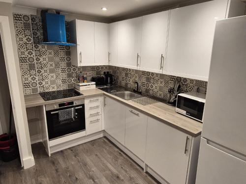 a kitchen with white cabinets and a sink at St Patrick Square Main Door in Edinburgh