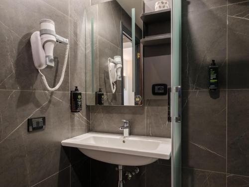 a bathroom with a sink and a mirror and a phone at B&B Hotel Faenza in Faenza