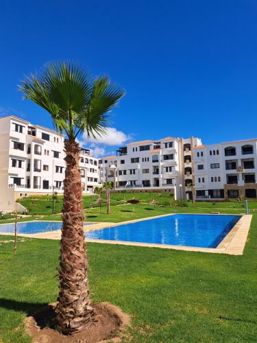a palm tree in front of a building with a pool at Cabo Negro-Lilac's Garden in Cabo Negro