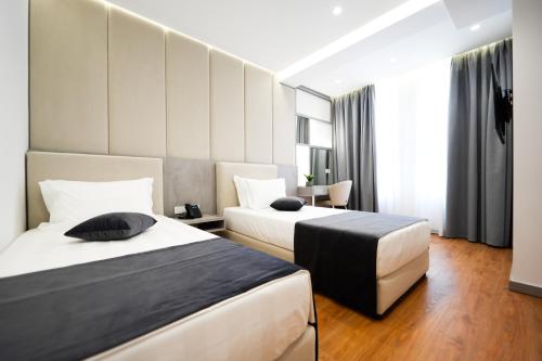 a hotel room with two beds and a desk at Naos Luxury Hotel in Vlorë
