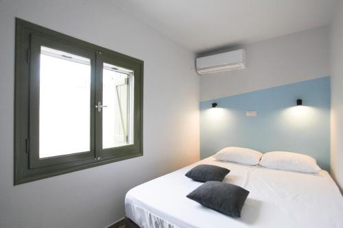 a bedroom with a white bed with a window at La Piccola Casa in Aegina Town