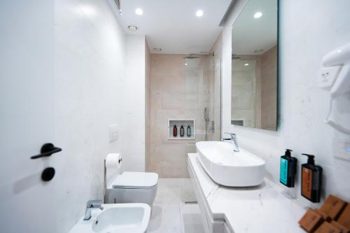 a bathroom with a sink and a toilet and a mirror at Naos Luxury Hotel in Vlorë