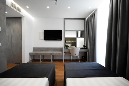 two beds in a room with a desk and a mirror at Naos Luxury Hotel in Vlorë