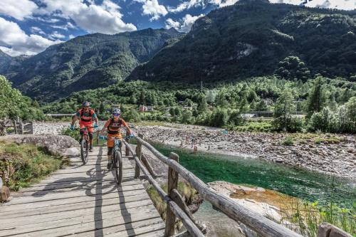 due persone che vanno in bicicletta su un ponte sopra un fiume di Hotel Pizzo Vogorno a Vogorno