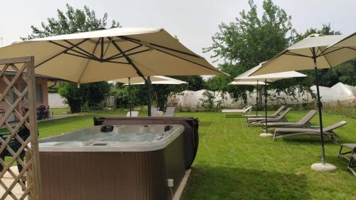 a hot tub with umbrellas in a yard at Hotel Ristorante alla Campagna in San Giovanni Lupatoto