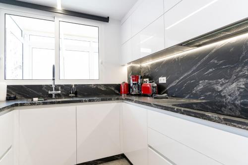 eine Küche mit weißen Schränken und einer schwarzen Arbeitsplatte in der Unterkunft rentafive - Luxury - Reformado - 2 min Gran Playa in Santa Pola