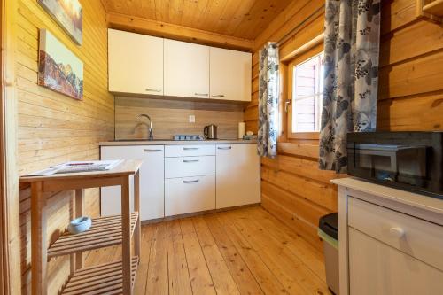 a kitchen with white cabinets in a wooden cabin at Chaty Snowflakes v Snowpark Lučivná in Lučivná
