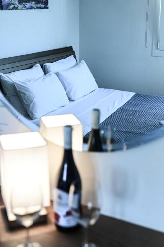 a bed with two bottles and two glasses on a table at BIG BLUE HOTEL in Amaliápoli