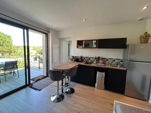 une cuisine avec une table et un réfrigérateur dans l'établissement Appartement neuf T2 avec jardin et terrasses, à Arcachon