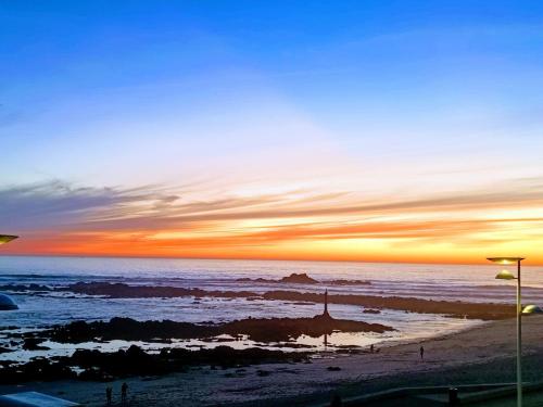 a sunset on a beach with the ocean at Cachinnans Hostel & Apartments in Vila do Conde