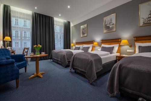 a hotel room with three beds and a table and chairs at Prague Season Hotel in Prague