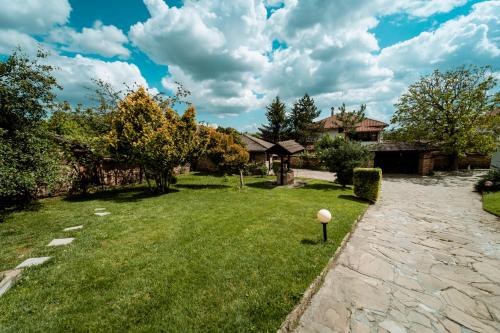 a yard with a stone walkway and trees and houses at Hotel Winpalace in Arbanasi