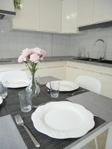 une cuisine avec des assiettes blanches et des fleurs roses sur une table dans l'établissement Le Virlogeux - Central & Paisible, à Riom