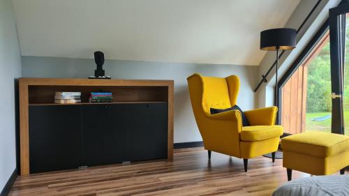 a living room with a yellow chair and a television at Mazurskie Wzgórze Nad Jeziorem Isąg in Pelnik