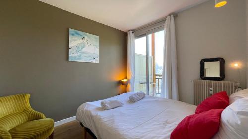 ein Schlafzimmer mit einem Bett und einem Stuhl und einem Fenster in der Unterkunft Homency - Résidence Belvédère D5 in L'Alpe-d'Huez